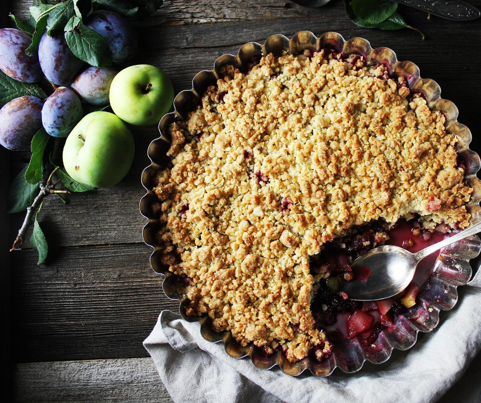 a pie with a spoon in a pan next to fruit